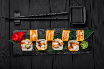 Traditional delicious fresh sushi roll set on a black background . Sushi roll with rice, cream cheese, salmon.