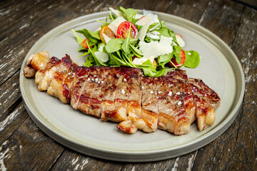 Cut of meat with fresh salad on a rustic wooden board