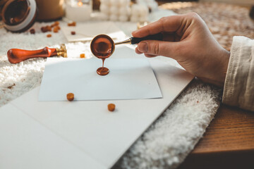 Girl making greeting card and sealing the envelope with wax sealing stamp