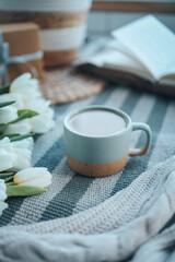 A cup of cappuccino, a bouquet of tulips, an open book and a gift, good morning aesthetics