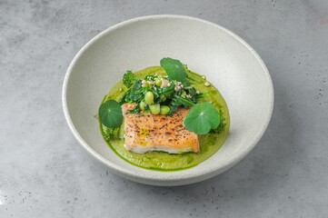 grilled cod in green sauce with blanched spinach and edamame beans on gray background