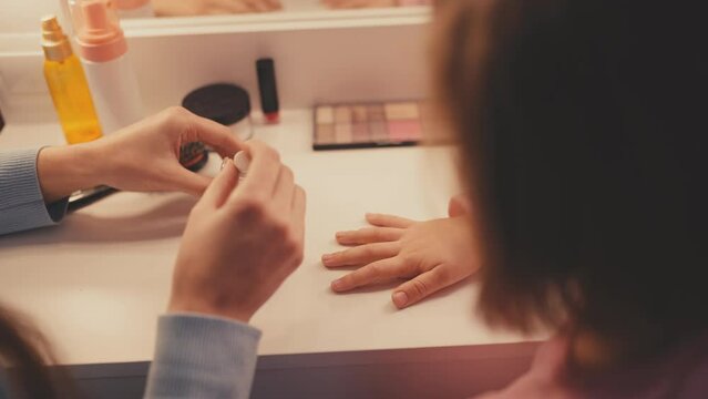 Top view of little girl and mom applying nail polish, family beauty rituals