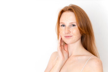 Obraz premium A natural portrait of a beautiful young red-haired girl on a white background. Light makeup. Self-care. freckles. Space for text.