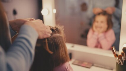 Close-up of woman braiding her little daughter's hair, getting ready for school