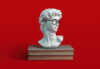 stack of books and sculpture of David's head with eyeglasses on red background. Student and...