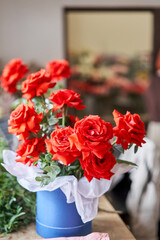 Red rose. Young woman making fashion modern bouquet in round blue box. Colorful color mix flower. Floral shop concept. Flowers delivery