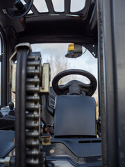 closeup of the lifting chain on a forklift truck with steering controls behind