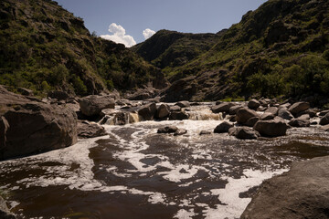 Panorama view of Yuspe river in the rock massif Los Gigantes in Cordoba, Argentina. View of the water flowing across the rocky hills.	