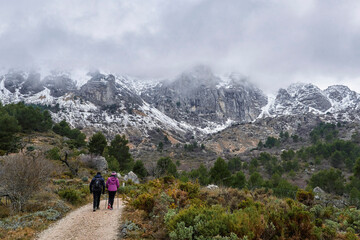 Fototapeta na wymiar Sierra de Aitana with snow. Couple hiking in Sierra de Aitana.The Sierra de Aitana is the highest point in the Province of Alicante with 1,557 meters of altitude. Located in Benifato, Alicante, Spain
