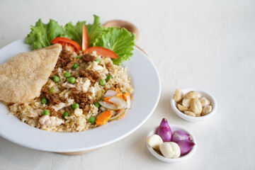 Chinese fried rice with kerupuk served in a white plate. on a white background