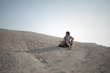 Fototapeta na wymiar young man in the desert sitting on the ground