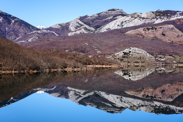 Obraz premium View since the Viewpoint of the porma reservoir, in the province of leon, on a sunny day with the Susarón peak and mountains reflected in the water of the reservoir. Castilla y Leon, Spain.