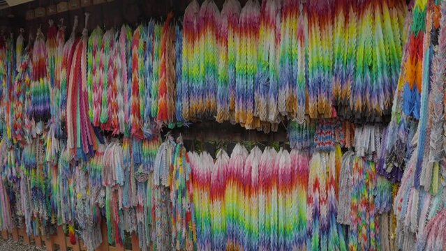This panning video shows thousands of rainbow colored prayer origami cranes hanging on temple walls.