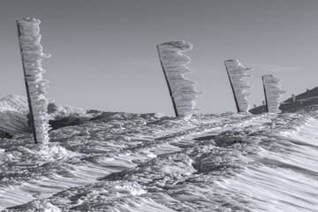 Black and white photo of winter columns covered with snow, the work of the wind in the mountains
