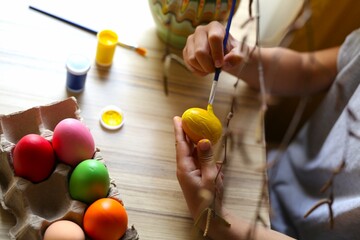 a seven-year-old child painted Easter eggs, the boy is at home, only the child's hands are in the frame, paint, brushes, top view