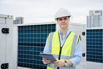 The engineer is inspecting the cooling tower air conditioner in a large industrial building to...
