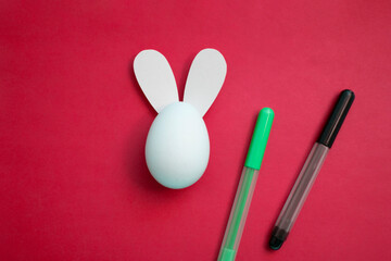 Religious holiday celebration concept. Coloring for children for Happy Easter. White chicken egg with rabbit ears. Green felt tip pen and black marker on trendy magenta color background 2023. Bunny