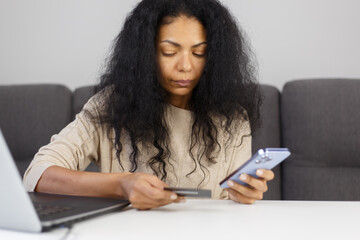 Young adult POC woman paying online with credit card and smart phone app. Portrait of customer making a purchase in mobile application