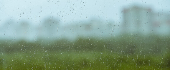 Atmospheric minimal backdrop with rain droplets on glass. Wet window with rainy drops and dirt...