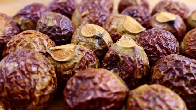 Brown dry soap nuts (Soapberries, Sapindus Mukorossi, Reetha) for organic laundry and gentle natural skin care circle rotation close up