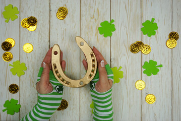 Women's hands hold a golden horseshoe on St. Patrick's Day. St. Patrick's Day celebration. The...