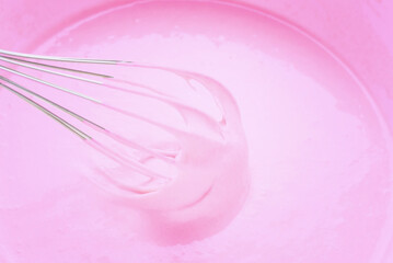 Whipping with a metal whisk of pink cream for baking