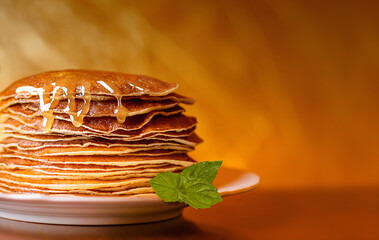 Ruddy pancakes with honey and fresh mint leaves on a yellow background
