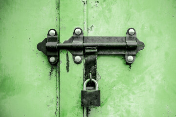 Grunge garage door. Black padlock texture. Metal entrance. Old peeling paint gate. Aged car garage iron door. Green color paint.