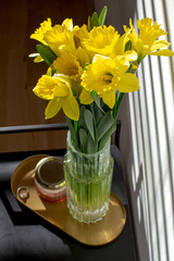 Bouquet of yellow daffodils on a coffee table with an unusual shadow on the wall