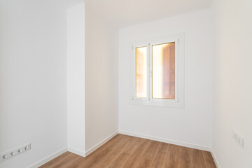 Part of an empty room with white walls, brown parquet. Plastic window in wall with frosted translucent glass. Socket is built into wall for simultaneous connection of several electrical appliances.