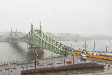 Fototapeta na wymiar Green bridge over the river with yellow tram