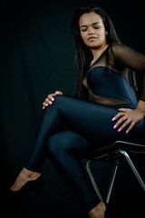 Fototapeta na wymiar Portrait of a beautiful young Brazilian woman sitting on a stool and wearing a skintight body suit