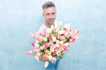 man with valentines tulips in studio, selective focus. man with valentines tulips isolated on blue