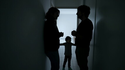 Couple discussing relationship with child in the middle. Silhouettes of man and woman conversation standing at home corridor. Parents talking