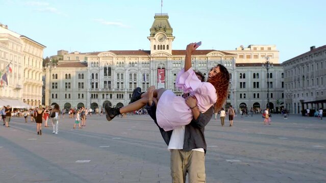 young couple enjoing sunset together in piazza unit&agrave; in trieste taking a selfie