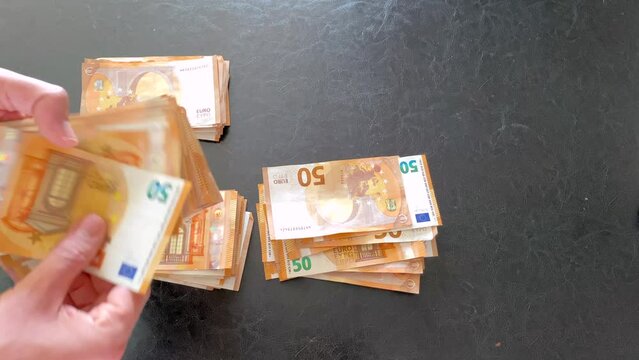 Counting 50 euro cash and splitting it into stacks money banknotes bill close up