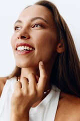 Portrait of a young beautiful woman with tanned skin model on a white background in a white T-shirt with a chain around her neck