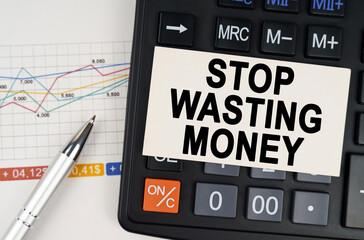 On the business chart lies a pen, a calculator and a business card with the inscription - Stop wasting money