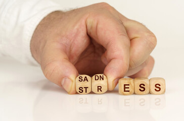 On the reflective surface in the hands of a man are cubes with the inscription - SADNESS or STRESS