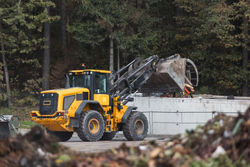 Skid steer loader moving garbage at the landfill site, before processing waste material, sorting, treatment, or recycling