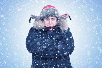 Frozen man in winter clothes warms his hands in his sleeves, on a light blue background with snow