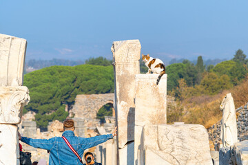 Tourists pose alongside one of the many stray cats who lounge and sleep on the marble statues and columns in the ancient city of Ephesus, Turkey.