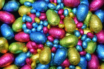 Pile or group of multi colored and different sizes of colourful foil wrapped chocolate easter eggs...