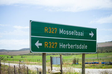 Western Cape, South Africa - December 23rd, 2022: A direction sign on the R327 road, between the towns of Herbertsdale and Mossel Bay, pointing the direction of both towns.