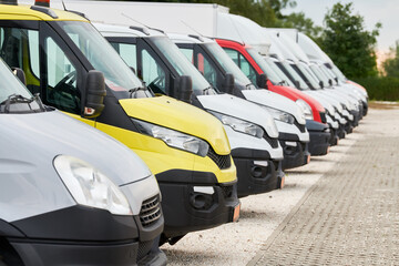 Fleet of commercial van trucks in row. Logistics and transportation service company