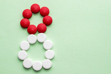 digit number 8 from white and red round shape pills isolated on green paper background.women mother international day concept,mock up template copy paste for greeting card banner march 8th