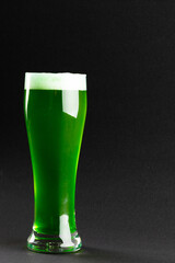 Image of glass with green beer and copy space on grey background
