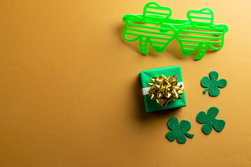 Image of green glasses, green clover, green present and copy space on orange background © vectorfusionart