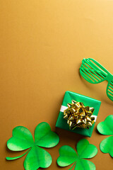 Image of green glasses, green clover, green present and copy space on orange background © vectorfusionart