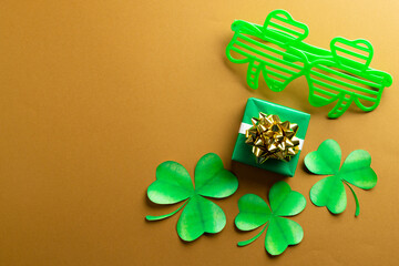 Image of green clover glasses, green clover, green present and copy space on orange background © vectorfusionart